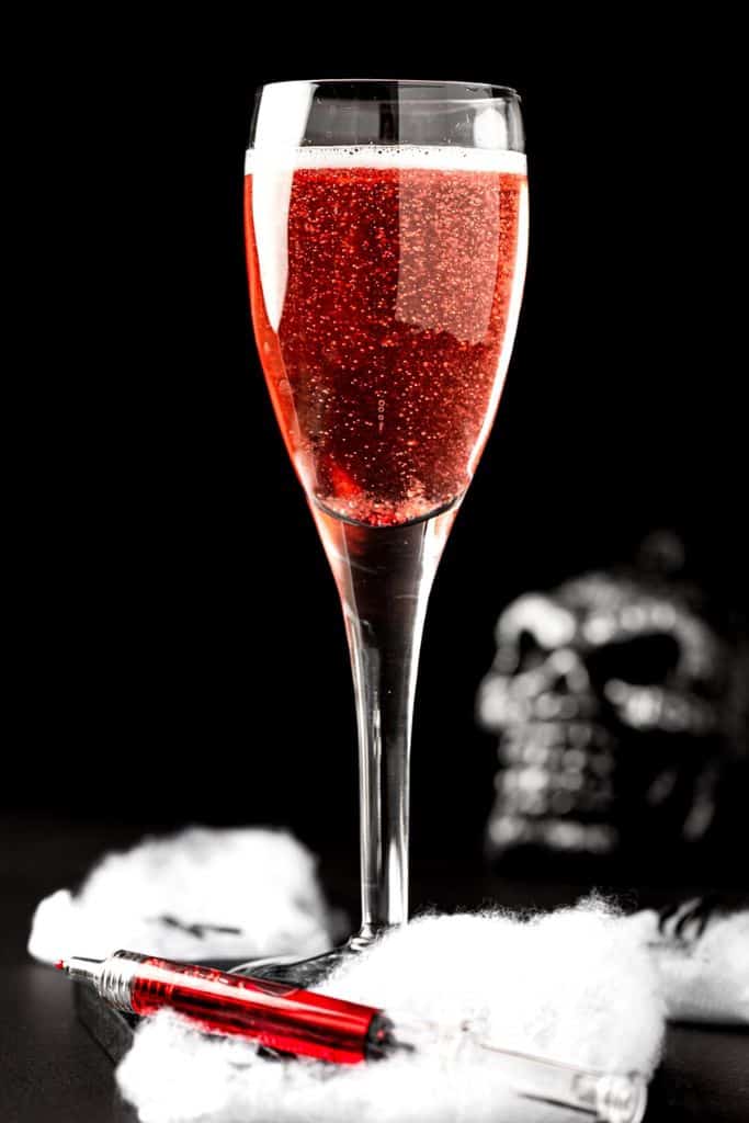 red halloween mimosa cocktail in champagne glass.
