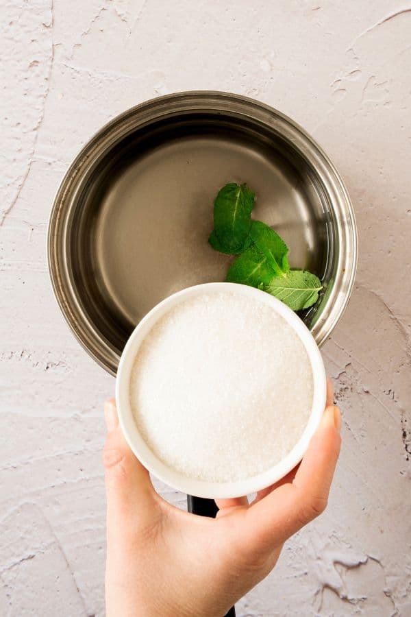 adding sugar to saucepan to make simple syrup.