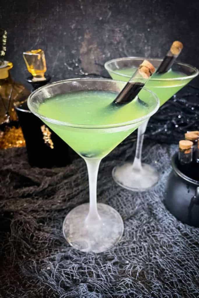 green cocktail in glass with black shot.