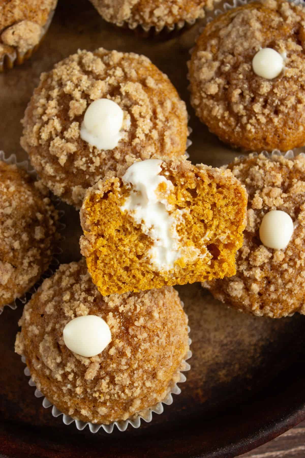 closeup of halved pumpkin cheesecake muffin sitting atop other pumpkin muffins.