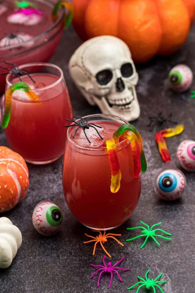 red halloween punch in glass with lolly snakes and plastic spiders.