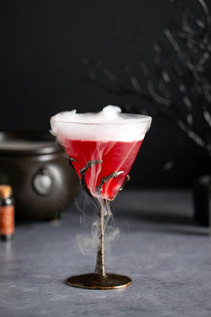 red cocktail with dry ice in glass.