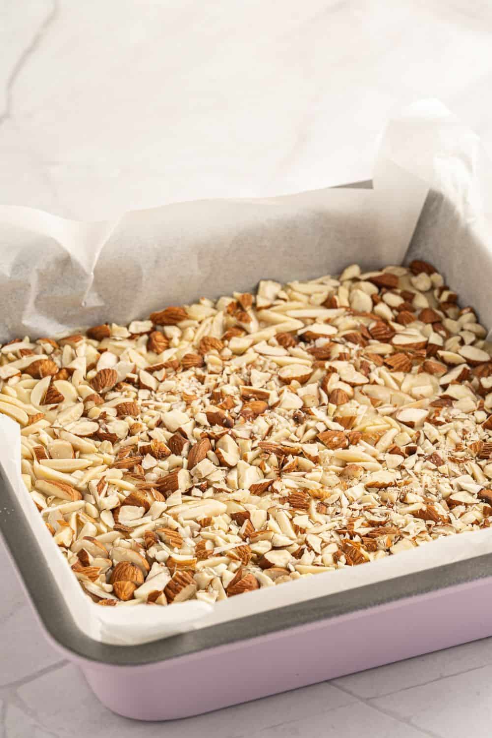 white chocolate fudge topped with chopped almonds in lined pan.