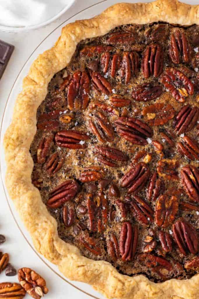 whole chocolate pecan pie in glass dish.
