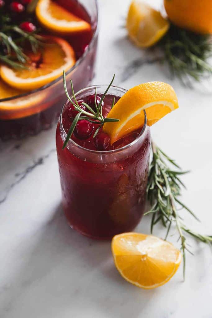 cranberry punch in glass with fresh fruit garnish.