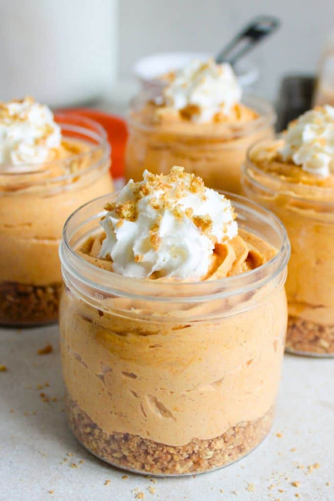 pumpkin cheesecake cups with cream on top.