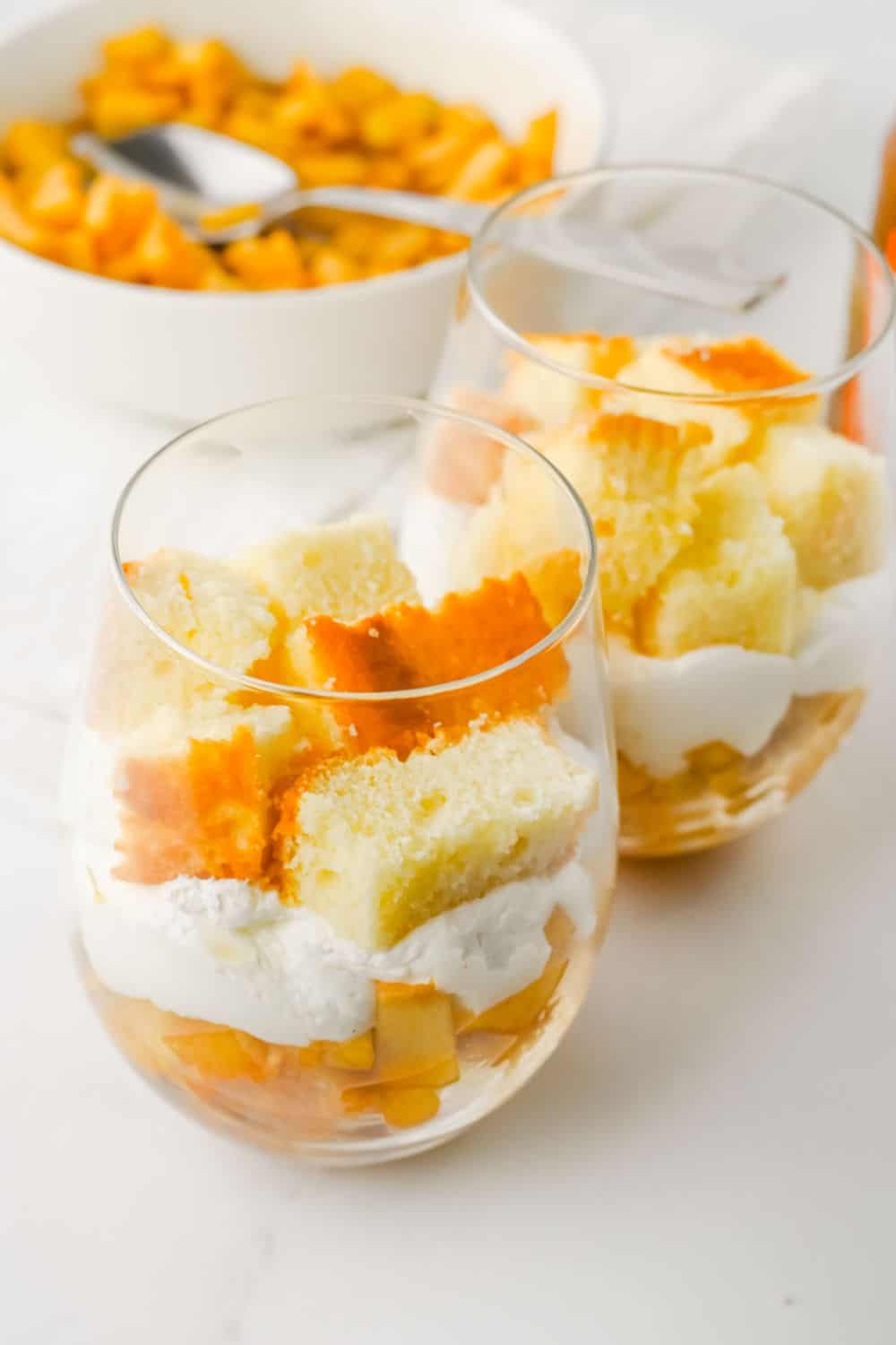 layers of pound cake, apple, and cool whip in glasses.