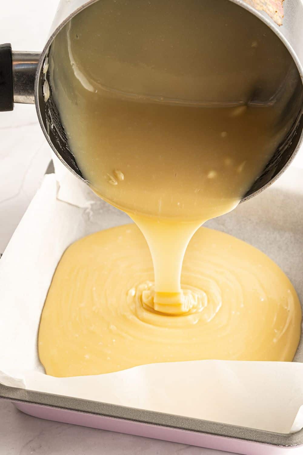 pouring fudge mixture into lined pan.