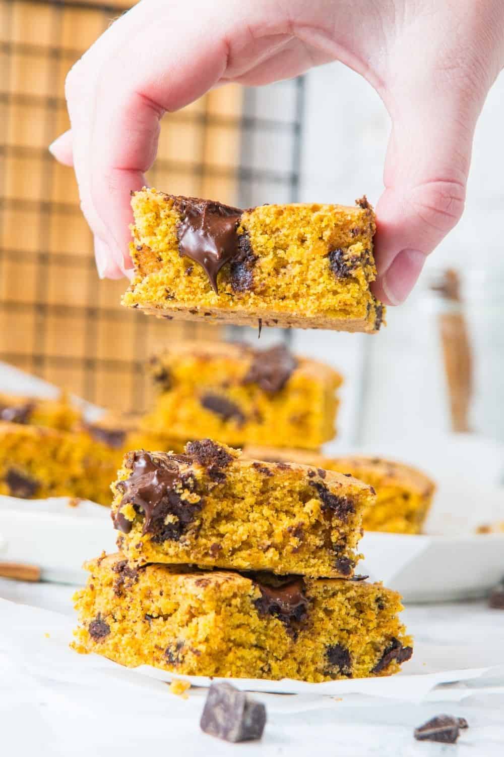 stack of pumpkin cookie bars with person lifting top bar off.