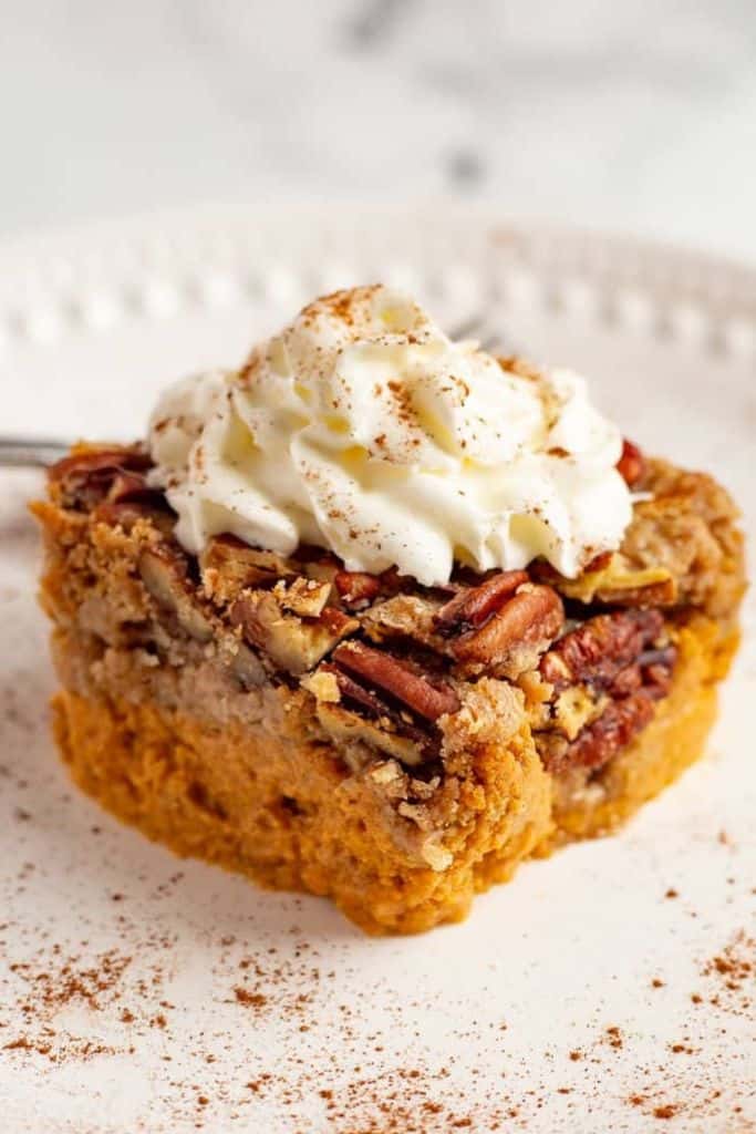 slice of pumpkin pecan dump cake with cream.