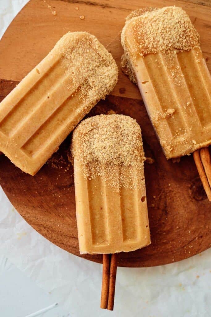 pumpkin popsicles on wooden board.