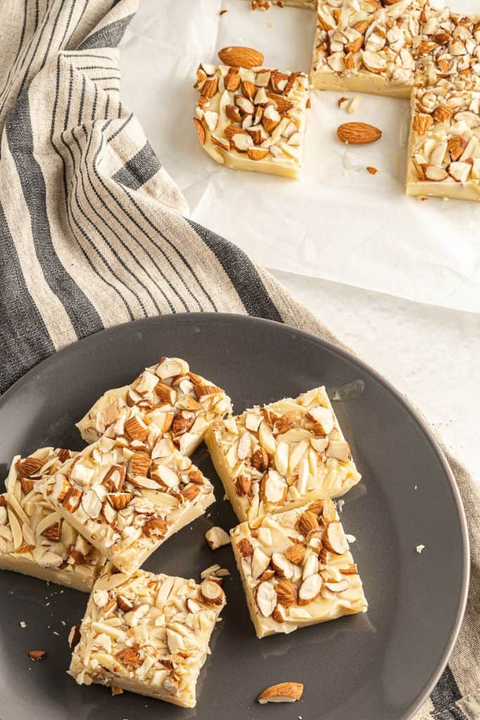 squares of white chocolate fudge with almonds on plate.