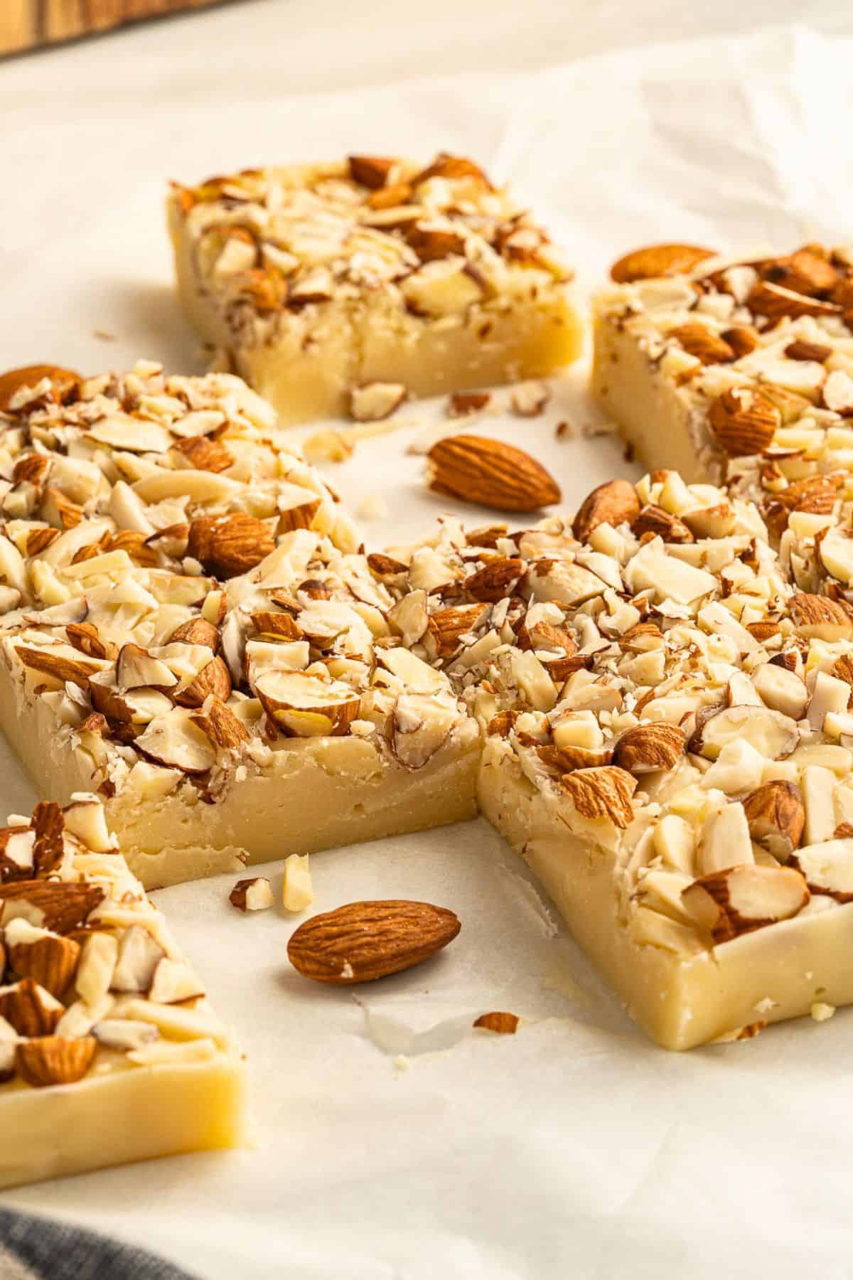 pieces of white chocolate fudge with almonds on parchment paper.