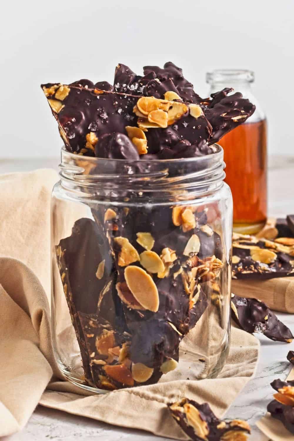 dark chocolate almond bark pieces in glass jar.