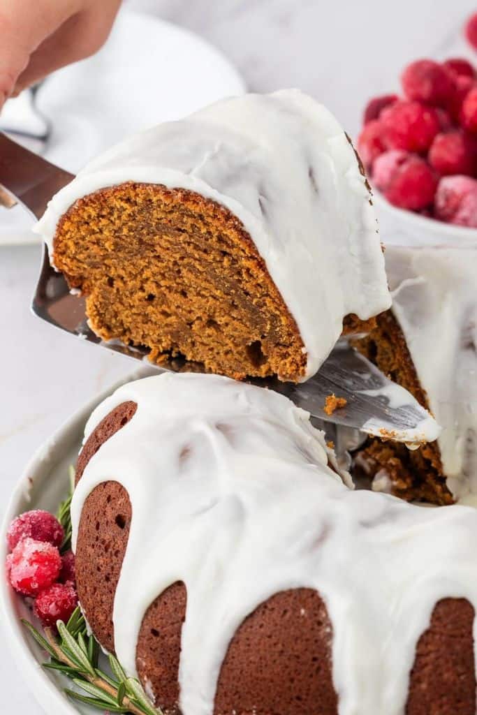 piece of gingerbread bundt cake with icing lifted on serving spoon.