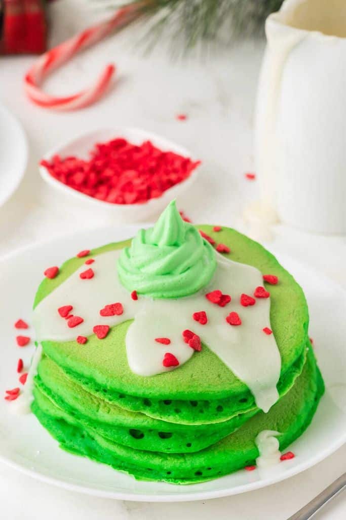 stack of green grinch pancakes with love heart candy.