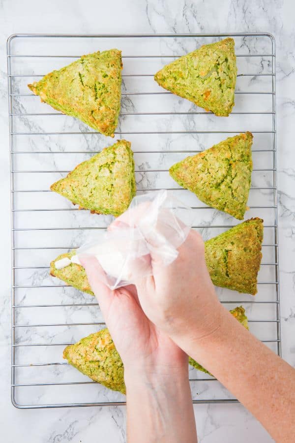 piping cream cheese on scones on wire rack.