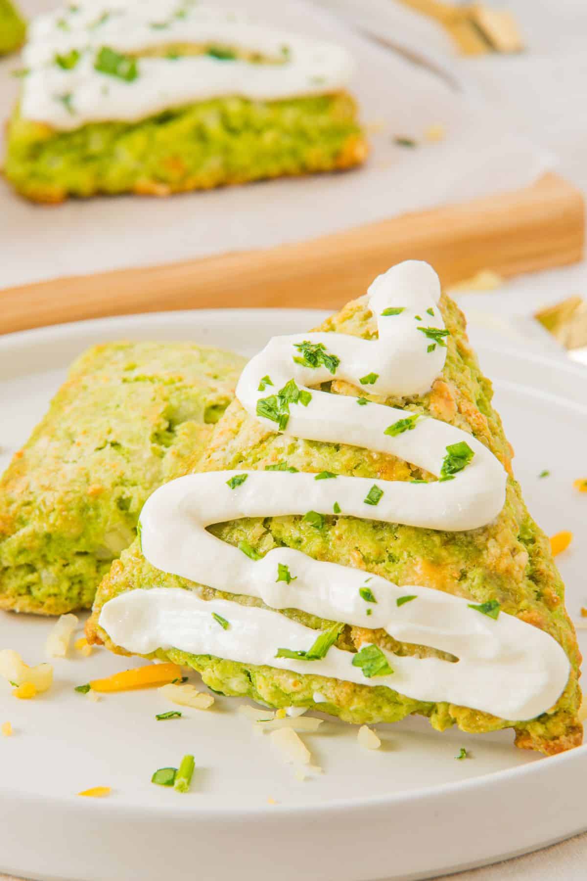 savory scones on plate with cream cheese drizzled on top.
