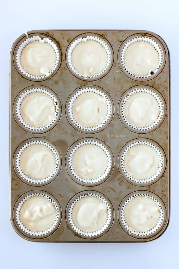 white cupcake mixture in cases in muffin pan.